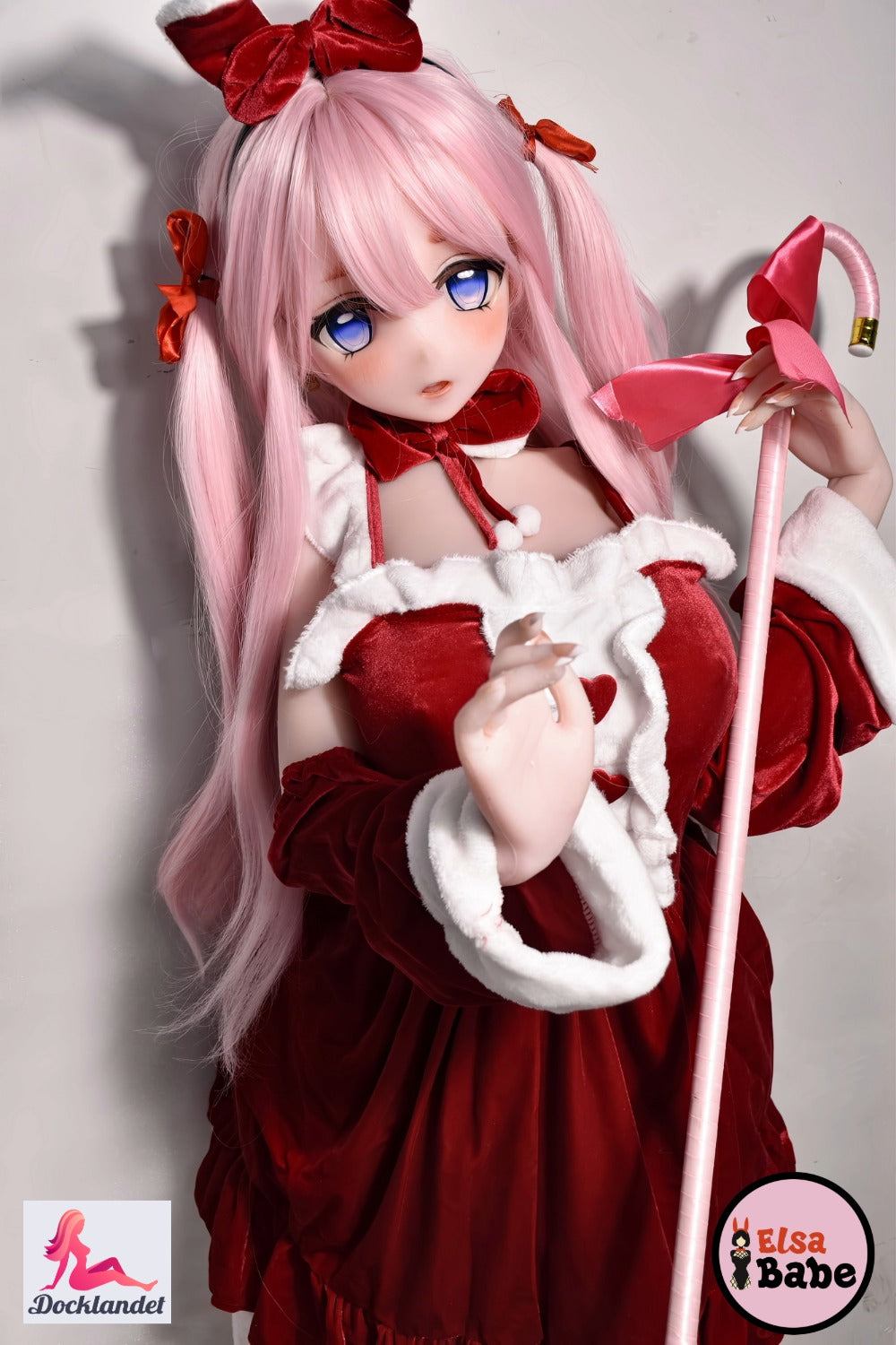 ElsaBabe Itsuki Sango 148 cm anime waifu nukk, kannab punast ja valget kaaridega jõulukleiti, roosade juuste ja siniste silmadega, hoiab käes suure kaarega roosat pulka.